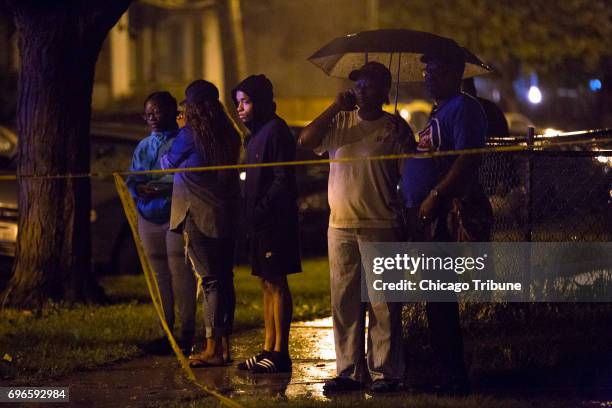 Rain pours down as people stand at the scene of a fatal shooting in the 5900 block of West Thomas Street Friday, June 16 in the Austin neighborhood...