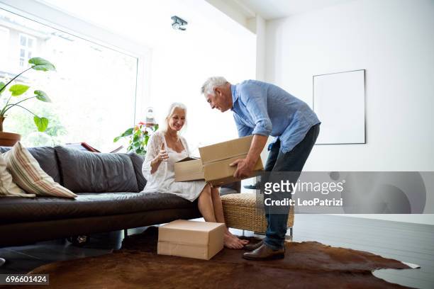 (echt) paar genieten van het dagelijkse leven en pensioen. senioren thuis - man with moving boxes authentic stockfoto's en -beelden