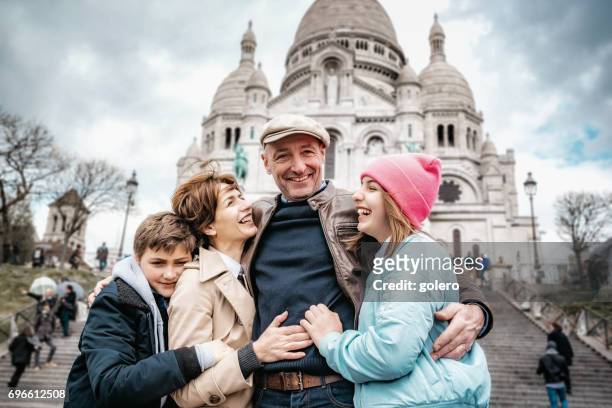 happy french family embraced in front of sacre coeur in paris - french culture stock pictures, royalty-free photos & images