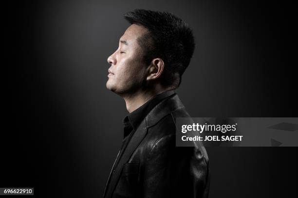 Chinese artist Liu Bolin poses during a photo session in Paris on June 10, 2017.