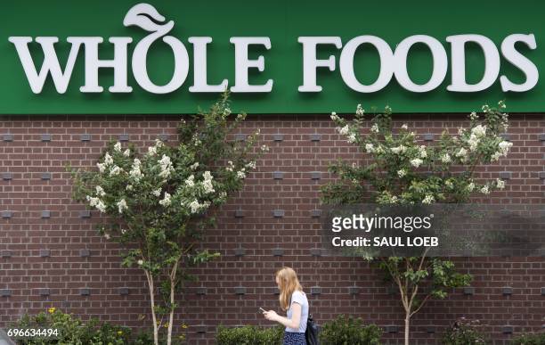 Woman walks past a Whole Foods Market in Washington, DC, June 16 following the announcement that Amazon would purchase the supermarket chain for...