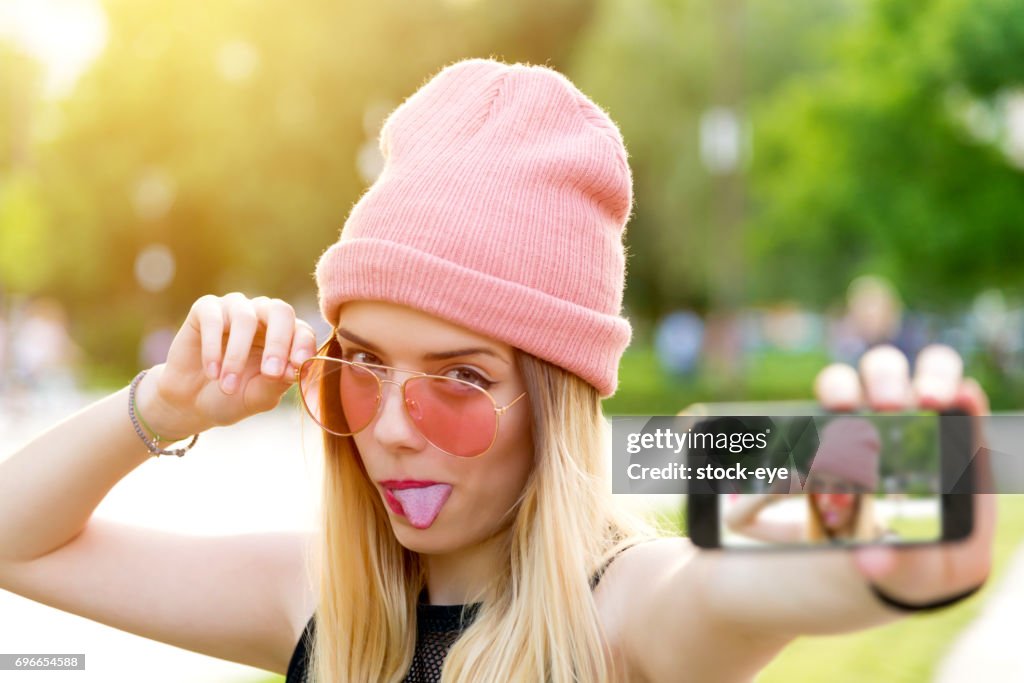 Beautiful young hipster girl makes self portrait on smartphone view of screen