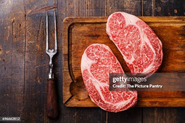 raw fresh marbled meat steak ribeye black angus and meat fork on wooden background copy space - marmoriertes fleisch stock-fotos und bilder