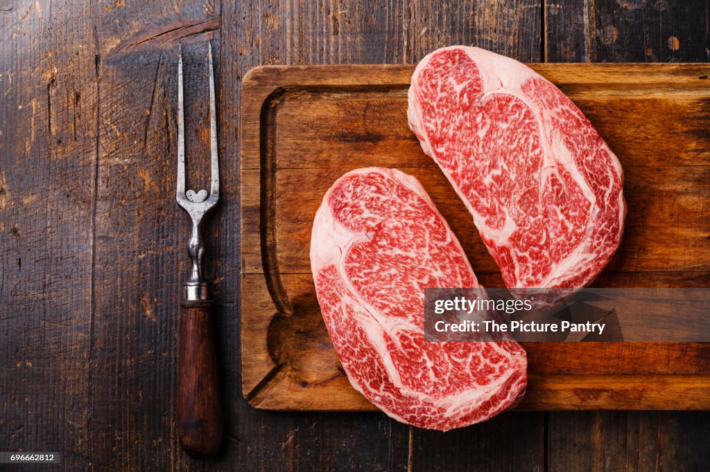 Raw fresh marbled meat Steak Ribeye Black Angus and meat fork on wooden background copy space