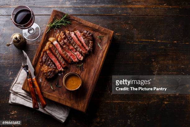 grilled sliced steak rib eye with pepper sauce and red wine on wooden background copy space - lob wedge stock-fotos und bilder
