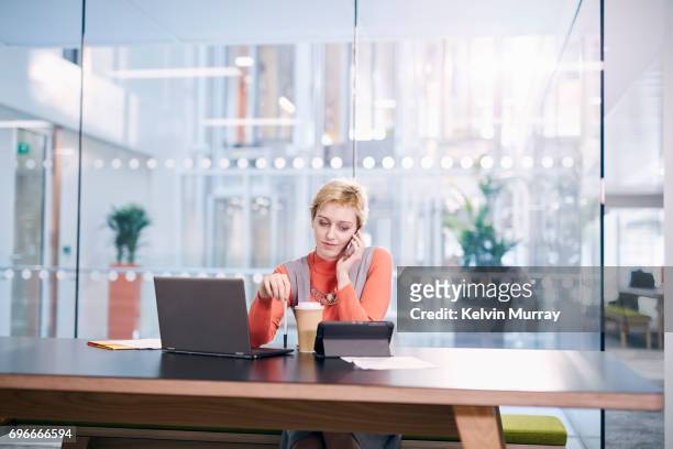 creative businesswoman using cell phone in conference room - blonde business woman stock pictures, royalty-free photos & images