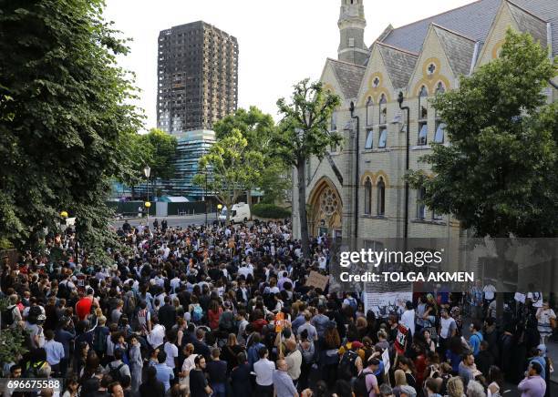 The shell of Grenfell Tower looms over protesters gathering at Notting Hill Methodist Church after marching back from Kensington Town Hall in west...