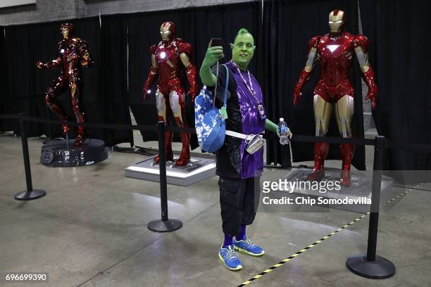 Mike Becvar of South Riding, VA, wears a Beast Boy costume while taking a selfie with lifesize Ironman models in the Stan Lee Museum exhibit during...