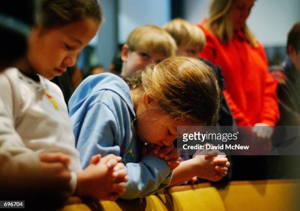 Susan bows her head in prayer as she and fellow fourth-grader Carolyne attend a prayer service to give thanks that no one has died since a car plowed...