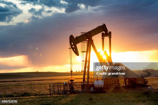 fracturamiento hidráulico de la bomba jack al atardecer con puesta de sol - fracking fotografías e imágenes de stock