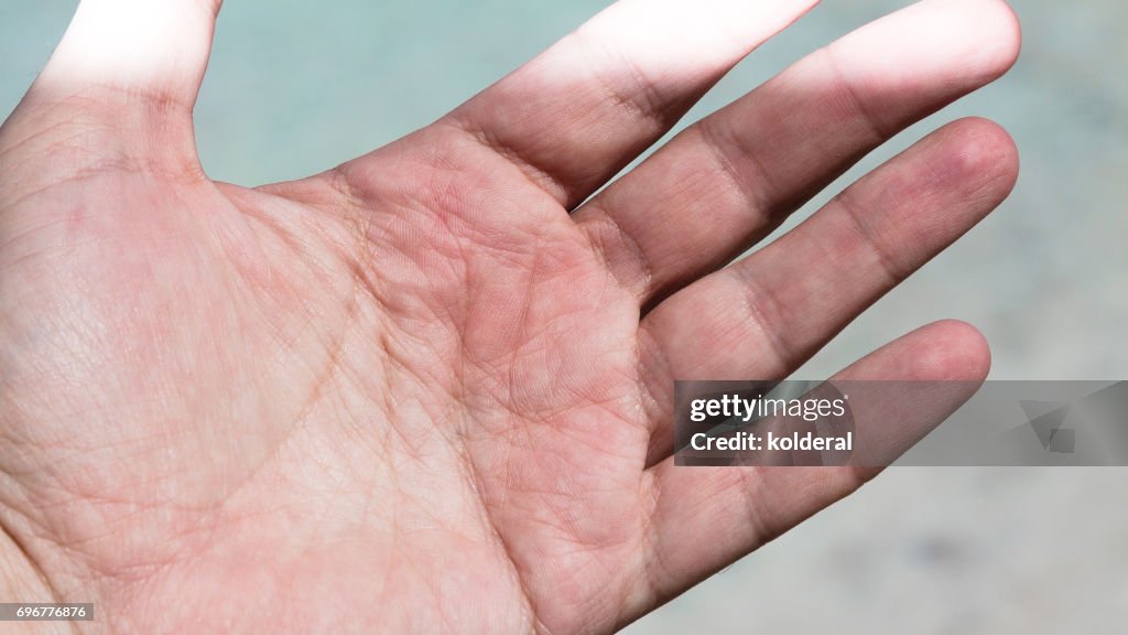 Close up shot of palm side of man's hand partly illuminated by sunbeam