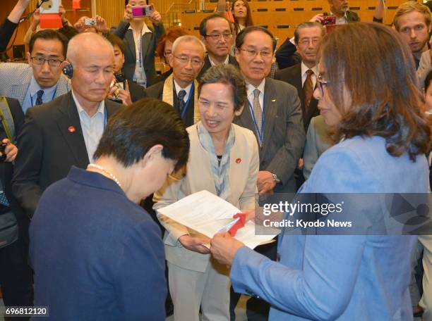 Japanese atomic bomb survivors or hibakusha -- Toshiyuki Mimaki and Masako Wada -- hand over a petition with nearly 3 million signatures demanding...