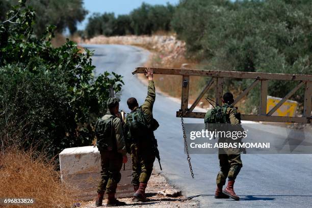 Israeli soldiers close a gate leading to the village of Deir Abu Mashal near the West Bank city of Ramallah, on June 17 following an attack by three...