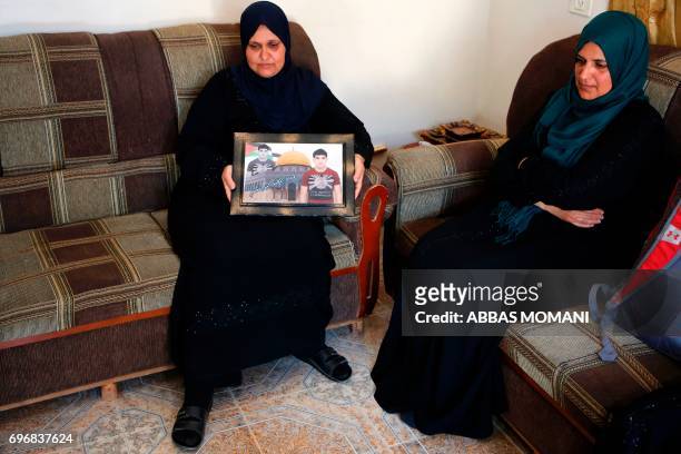 The mother of Osama Ata carries his picture at their home in the village of Deir Abu Mashal near the West Bank city of Ramallah, on June 17 following...