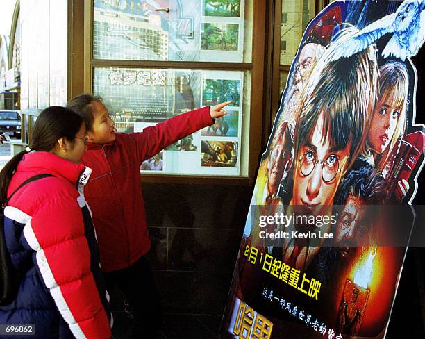 Young girl points to a Harry Potter movie poster February 1, 2002 as another young girl stands next to her in Beijing, China. More than three million...