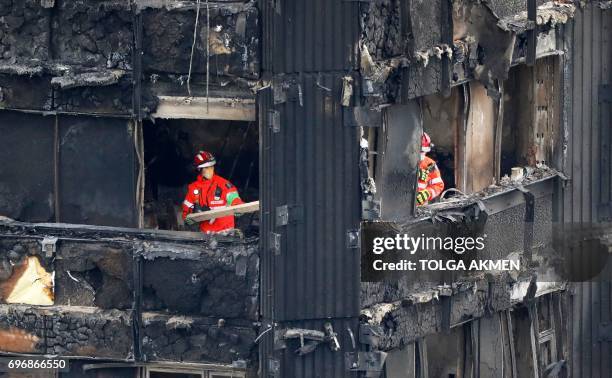 Members of the emergency services work on the middle floors of the charred remnains of the Grenfell Tower block in Kensington, west London, on June...