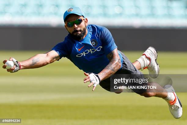 India's captain Virat Kohli dives to make a catch as he attends a nets practice session at The Oval in London on June 17 on the eve of the ICC...