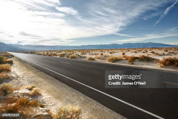 empty road in desert landscape with distant mountains - carretera vacía fotografías e imágenes de stock