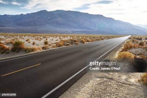 empty road in desert landscape with distant mountains - desert horizon stock pictures, royalty-free photos & images