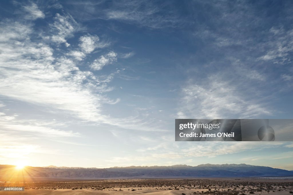 Sunset over open plane with distant mountains and large sky