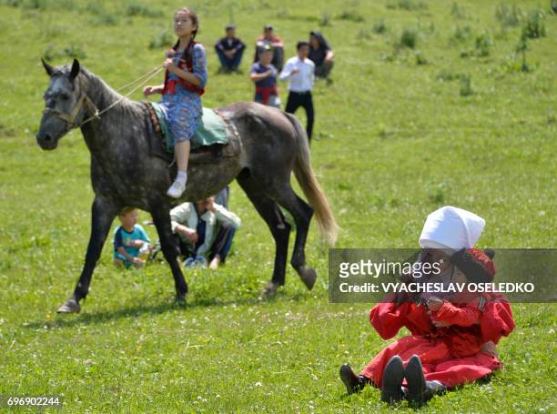 Kyrgyz woman wearing a traditional dress plays with a child during a folk festival at Kyrgyzstan's Chon-Kurchak valley, some 30km outside Bishkek, on...