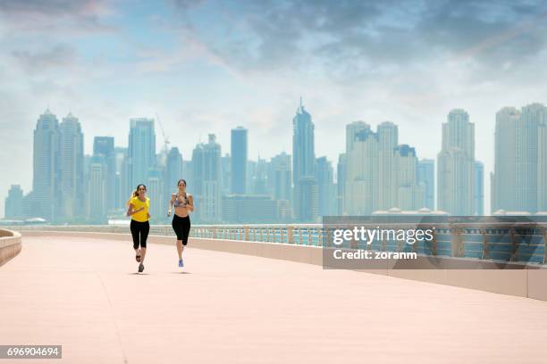 women jogging with cityscape in background - daily life in abu dhabi stock pictures, royalty-free photos & images