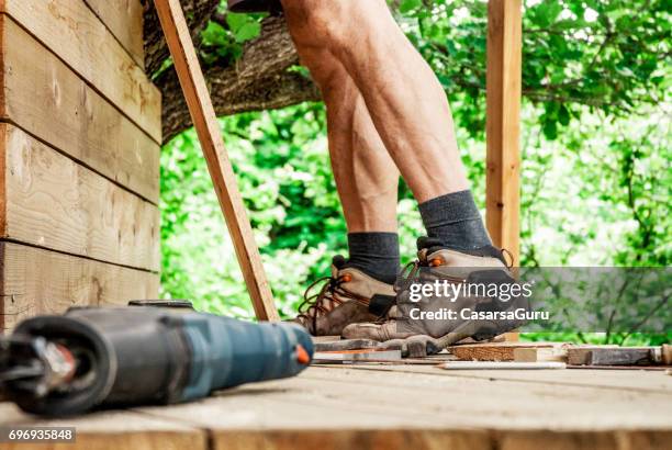 mitte erwachsener mann gebäude aus holz baumhaus - baumhaus stock-fotos und bilder