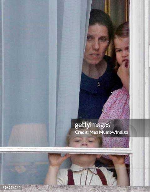 Prince George of Cambridge and Princess Charlotte of Cambridge, accompanied by their nanny Maria Teresa Borrallo, watch from a window of Buckingham...