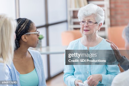 Emotional senior woman during group therapy session