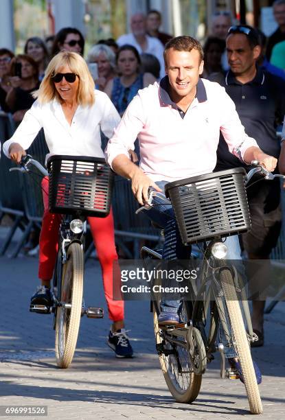 French President Emmanuel Macron and his wife Brigitte Trogneux leave their house on a bicycle on the eve of the second round of the French...