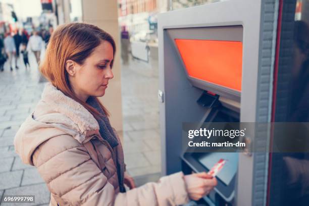 woman with debit card at the atm - high street bank uk stock pictures, royalty-free photos & images