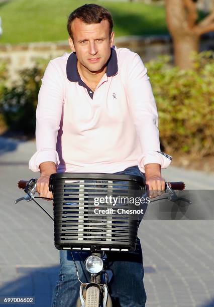 French President Emmanuel Macron returns to his house on a bicycle on the eve of the second round of the French parliamentary elections on June 17,...