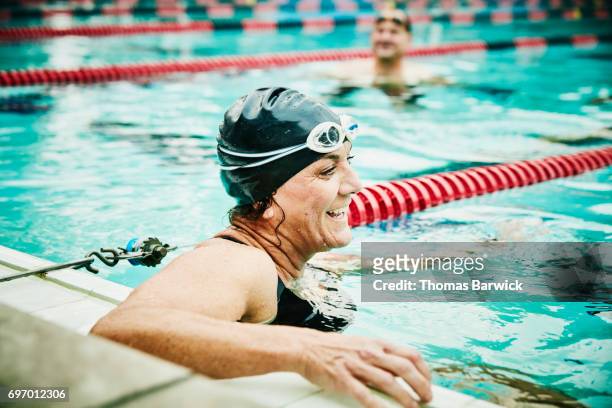 laughing mature swimmer resting between sets of early morning workout in outdoor pool - natación fotografías e imágenes de stock