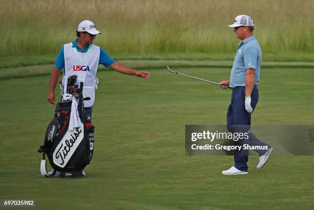 Charley Hoffman of the United States hands his club to caddie Brett Waldman on the 15th hole during the third round of the 2017 U.S. Open at Erin...