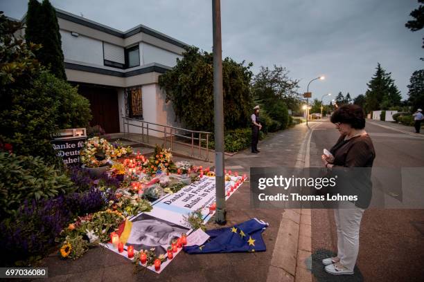 Mourner looks to flowers, candels and a portrait of Helmut Kohl in front of the home of former German Chancellor Helmut Kohl in Oggersheim district...