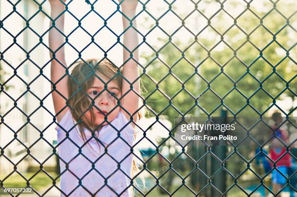 A young girl hanging from a fence.