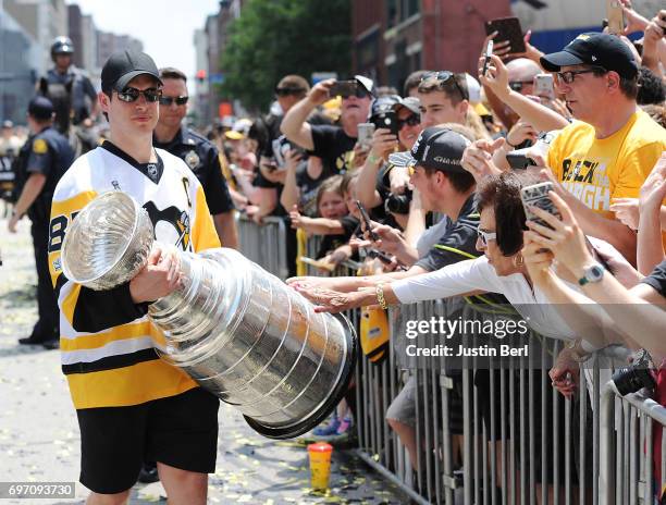 Sidney Crosby of the Pittsburgh Penguins walks with the Stanley Cup as fans touch it during the Victory Parade and Rally on June 14, 2017 in...