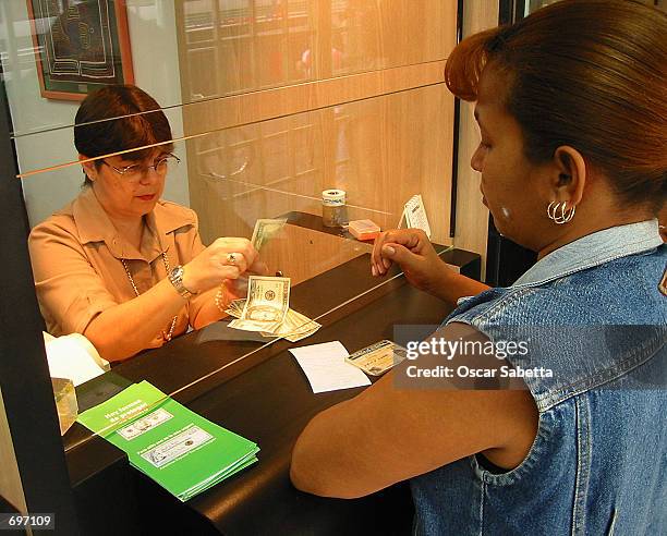 Venezuelan woman buys U.S. Dollars February 13, 2002 in a Caracas exchange house. Venezuelas bolivar currency tumbled nearly 15 percent against the...