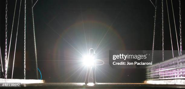 woman hula hooping with an illuminated plastic hoop at night. - strobe light stock pictures, royalty-free photos & images
