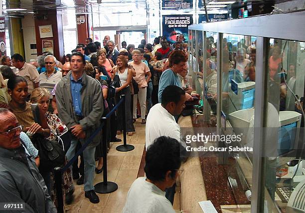 Customers wait to exchange bolivars into U.S. Dollars February 13, 2002 in Caracas, Venezuela. Venezuelas currency tumbled nearly 15 percent against...