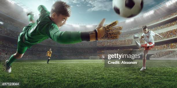 soccer kids players scoring a goal. goalkeeper tries to hit the ball - sports uniform stock pictures, royalty-free photos & images