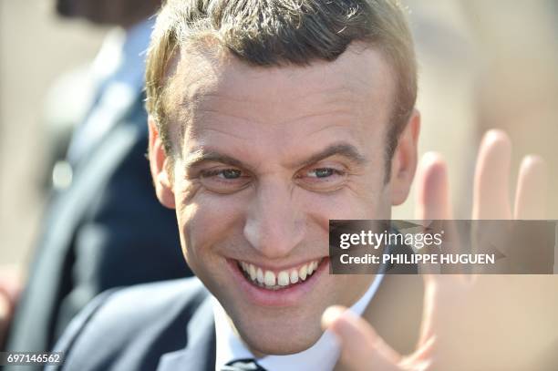 French President Emmanuel Macron smiles as he leaves his house to vote in Le Touquet, northern France, during the second round of the French...