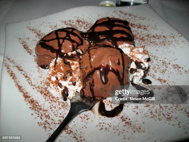 chocolate ice cream sundae with whipped cream, chocolate sauce and cocoa powder - chocolate sauce stock pictures, royalty-free photos & images