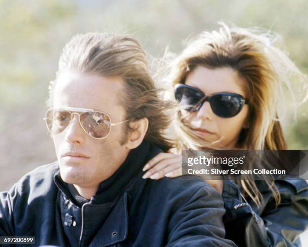 Actor Peter Fonda and singer Nancy Sinatra riding a motorcycle, both wearing sunglasses, in a scene from the film 'The Wild Angels', USA, 1966. The...
