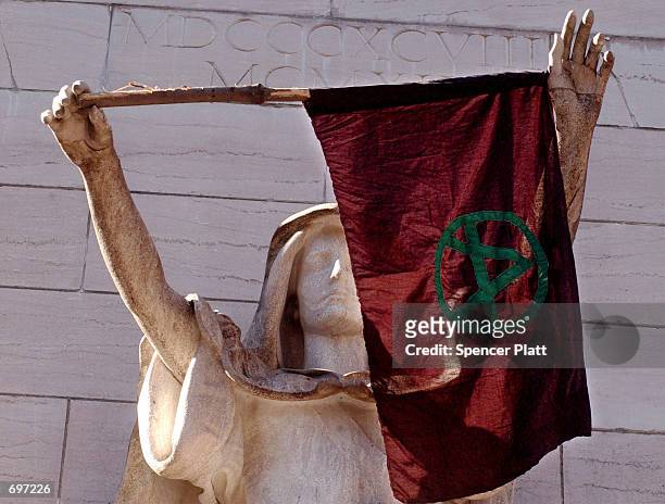 An anarchy flag hangs on a statue in Columbus Circle February 2, 2002 during an anti-World Economic Forum demonstration in New York City. Thousands...