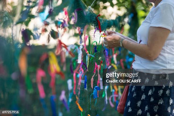 Woman symbolically ties a ribbon onto a piece of netting during a 'Great Get Together' community service and picnic in memory of Jo Cox, marking the...