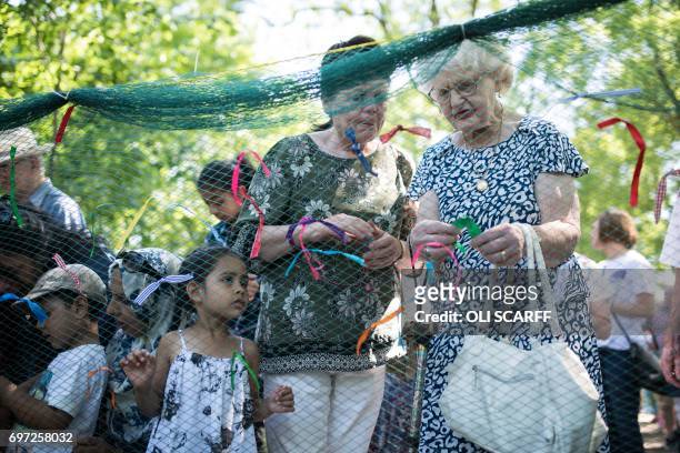 Members of the public symbolically tie ribbons onto a piece of netting during a 'Great Get Together' community service and picnic in memory of Jo...