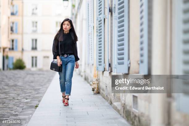 May Berthelot, fashion blogger and Head of Legal at Videdressing.com, wears a Harpe black lace top, The Kooples blue denim cropped jeans, a Gucci...