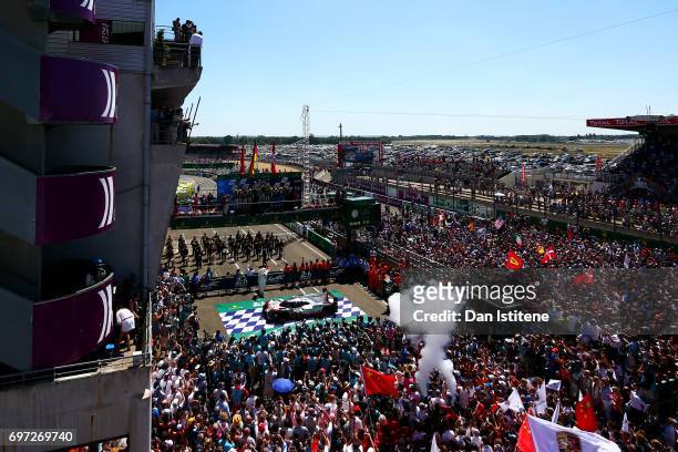 Fans fill the pit lane and pit straight as Earl Bamber, Brendon Hartley and Timo Bernhard of the Porsche LMP Team celebrate on the podium with Vice...