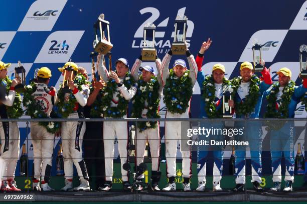 Brendon Hartley, Earl Bamber and Timo Bernhard of the Porsche LMP Team lift their trophies as they celebrate on the podium with Vice President of...